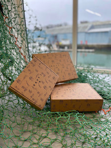 Three brown illustrated cardboard packing boxes laid in an arrangement on a green fishing net