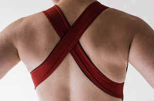 A close up of the back of a lady showing the cross back detail of a red Davy J Sustainable Waterwear swimsuit