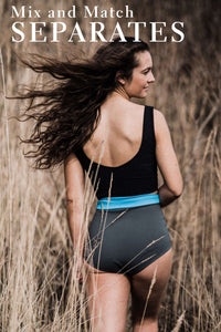 A lady walking through tall grass, wearing a black swim top and grey high waisted bikini briefs, looking back over her shoulder.  There is a text overlay which says 'Mix and Match Separates'