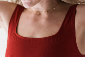A close up detail of the neckline of a red cropped Davy J Sustainable Waterwear swim top