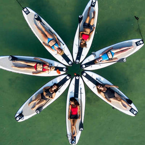 Drone footage of circle of women lying on paddle boards wearing colourful Davy J swimwear