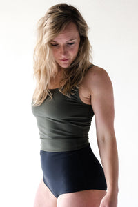 Blonde woman in studio looking down wearing Davy J Sustainable Waterwear olive green crop swim top and black high waist bikini briefs rolled down to show olive green lining